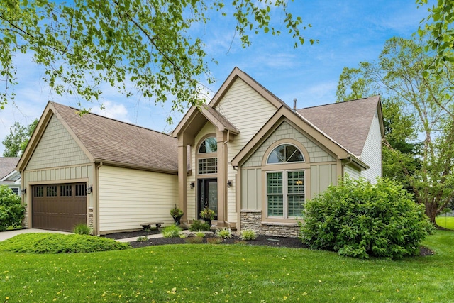 918 Dianthus Ct, Reynoldsburg, OH 43068 - view of front of home with board and batten siding, an attached garage, a front yard, a shingled roof, and stone siding