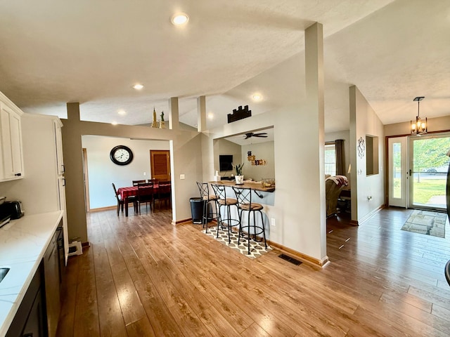 630 Duffy Dr, Washington Court House, OH 43160 - kitchen with vaulted ceiling, white cabinetry, wood-type flooring, a chandelier, and recessed lighting