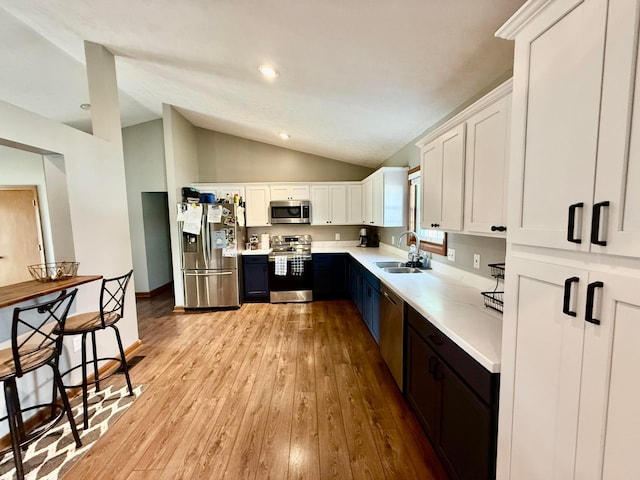 630 Duffy Dr, Washington Court House, OH 43160 - kitchen featuring appliances with stainless steel finishes, lofted ceiling, light wood-style flooring, light countertops, and white cabinets