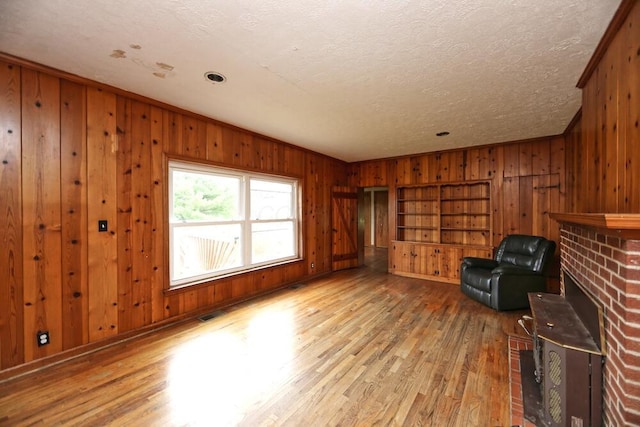 7579 Rangeline Rd, Mount Vernon, OH 43050 - unfurnished room with wooden walls, wood finished floors, a brick fireplace, and a textured ceiling
