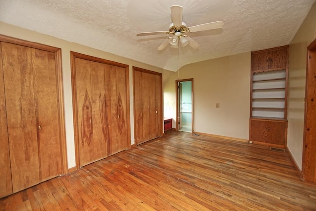 7579 Rangeline Rd, Mount Vernon, OH 43050 - unfurnished bedroom featuring hardwood / wood-style floors, multiple closets, a textured ceiling, and a ceiling fan
