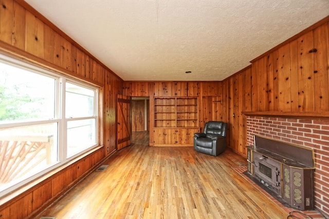 7579 Rangeline Rd, Mount Vernon, OH 43050 - unfurnished living room with wood walls, light wood-style floors, a textured ceiling, ornamental molding, and a fireplace