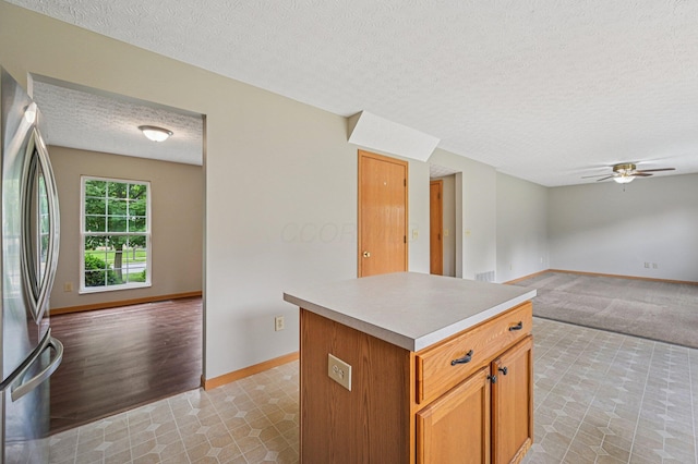 1016 Pebble Brook Dr, Columbus, OH 43240 - kitchen with freestanding refrigerator, a textured ceiling, open floor plan, ceiling fan, and a center island