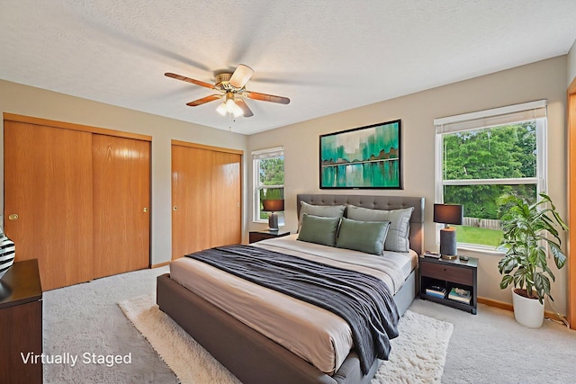 1016 Pebble Brook Dr, Columbus, OH 43240 - carpeted bedroom featuring two closets, a ceiling fan, and a textured ceiling
