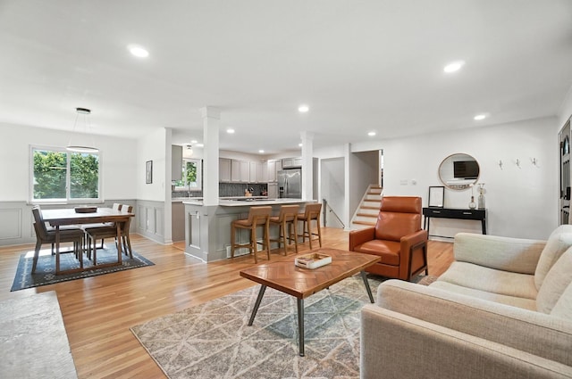 2820 Halstead Rd, Columbus, OH 43221 - living area featuring ornate columns, light wood-style flooring, a wainscoted wall, recessed lighting, and stairs