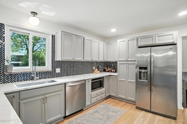 2820 Halstead Rd, Columbus, OH 43221 - kitchen featuring appliances with stainless steel finishes, gray cabinets, decorative backsplash, light wood-type flooring, and light stone counters
