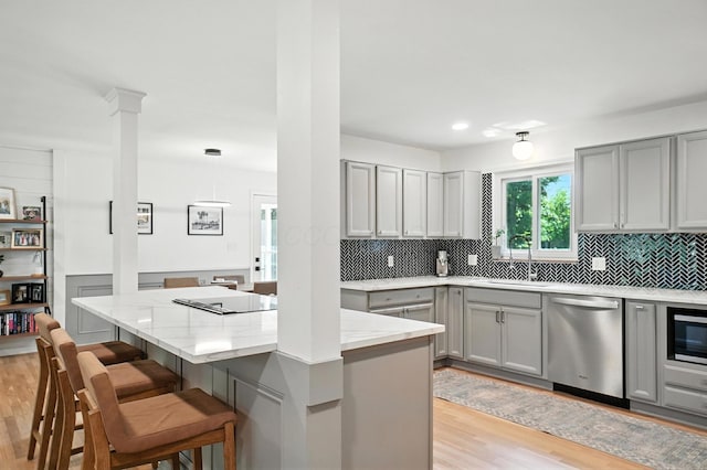 2820 Halstead Rd, Columbus, OH 43221 - kitchen featuring gray cabinetry, stainless steel dishwasher, light wood-style floors, and a breakfast bar area
