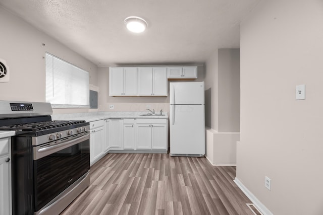 3505 Roswell Dr, Columbus, OH 43227 - kitchen featuring gas stove, freestanding refrigerator, light countertops, light wood-style flooring, and white cabinetry