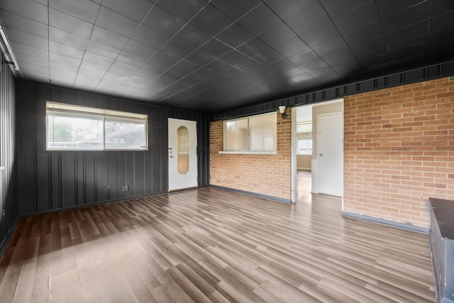3505 Roswell Dr, Columbus, OH 43227 - unfurnished living room with wood finished floors and brick wall