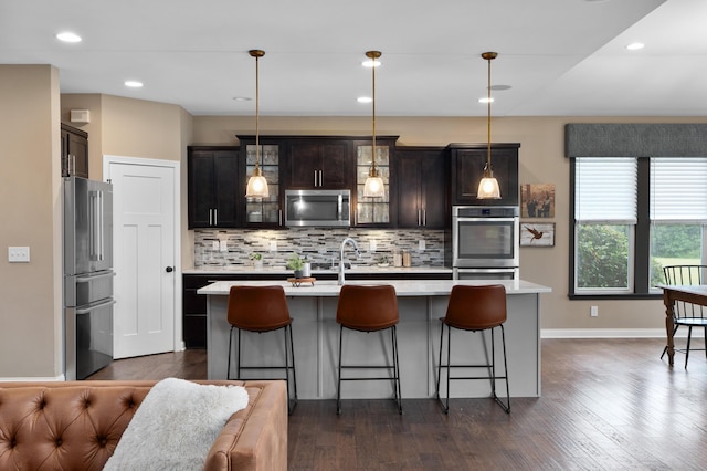 6196 Streamside Dr, Galena, OH 43021 - kitchen with stainless steel appliances, light countertops, backsplash, glass insert cabinets, and dark wood finished floors