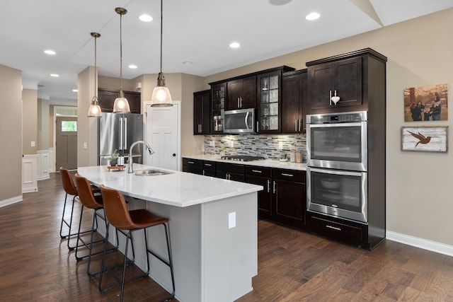 6196 Streamside Dr, Galena, OH 43021 - kitchen featuring appliances with stainless steel finishes, dark wood-style flooring, tasteful backsplash, a breakfast bar area, and glass insert cabinets