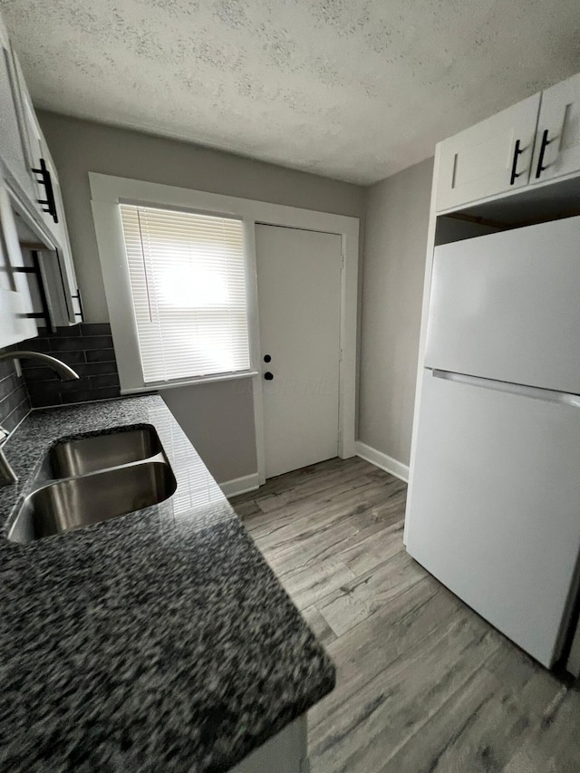 1116-1122 Cole St, Columbus, OH 43205 - kitchen with freestanding refrigerator, white cabinetry, backsplash, light wood-style flooring, and a textured ceiling