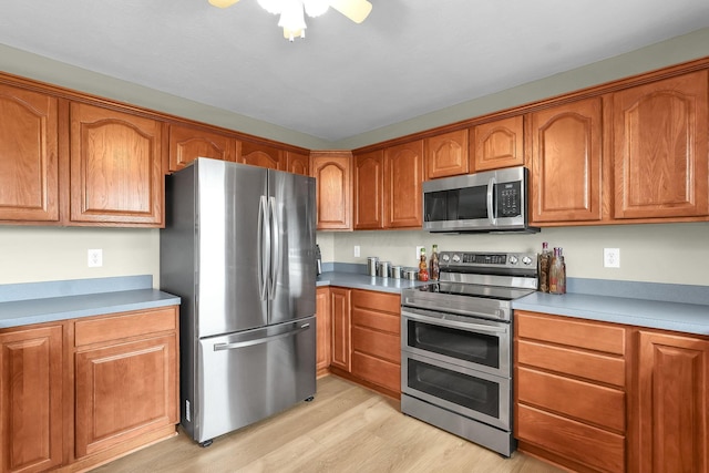 2110 Pickerington Rd, Carroll, OH 43112 - kitchen featuring stainless steel appliances, light wood finished floors, brown cabinetry, and ceiling fan