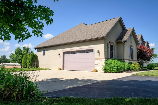 8150 Concord Rd, Delaware, OH 43015 - view of side of property with driveway, stucco siding, an attached garage, roof with shingles, and stone siding