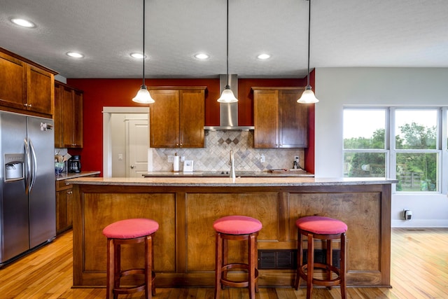8150 Concord Rd, Delaware, OH 43015 - kitchen featuring stainless steel fridge with ice dispenser, wall chimney exhaust hood, light wood-type flooring, tasteful backsplash, and decorative light fixtures