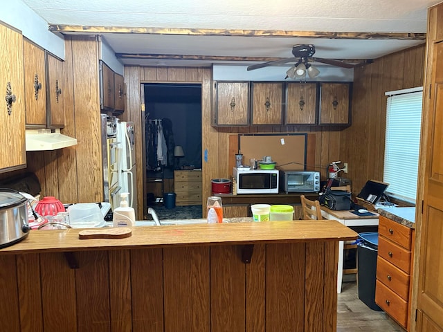 407 Marion St Unit 403, Mcguffey, OH 45859 - kitchen featuring a ceiling fan, wooden walls, white microwave, under cabinet range hood, and a peninsula