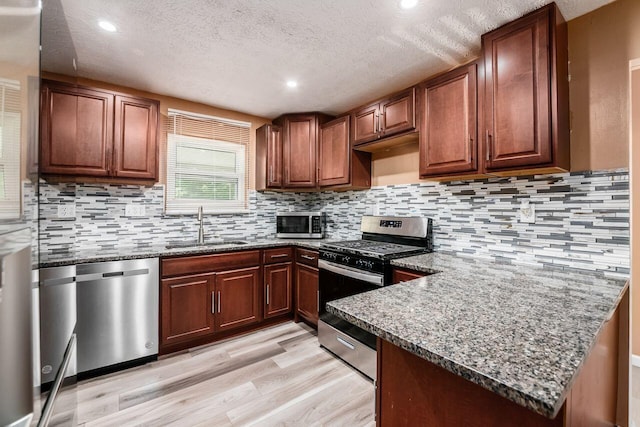 1914 Walden Dr, Columbus, OH 43229 - kitchen with stainless steel appliances, a textured ceiling, light wood-type flooring, dark stone counters, and a peninsula