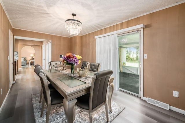 1914 Walden Dr, Columbus, OH 43229 - dining space featuring a chandelier, wood finished floors, arched walkways, crown molding, and a textured ceiling