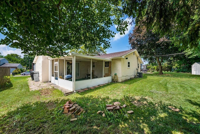 1914 Walden Dr, Columbus, OH 43229 - rear view of house featuring a sunroom, a storage unit, stucco siding, and a yard