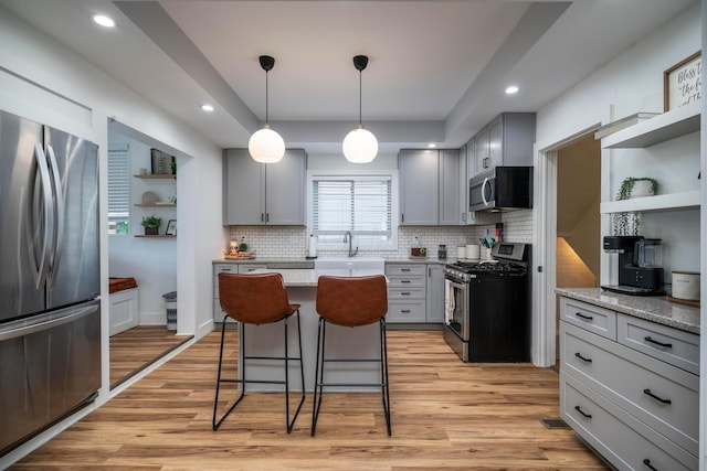 619 Columbus Ave, Washington Court House, OH 43160 - kitchen featuring appliances with stainless steel finishes, gray cabinetry, tasteful backsplash, a breakfast bar area, and light wood-style floors