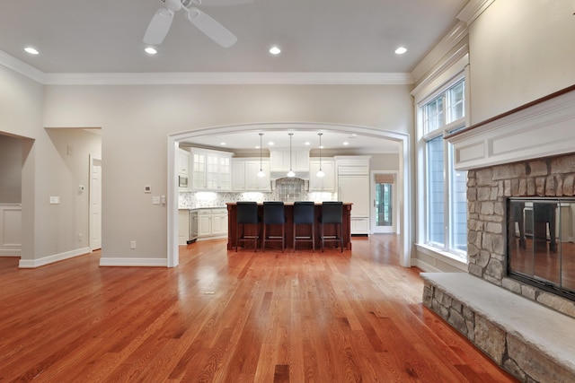 580 Keyes Ln, Worthington, OH 43085 - living room with ornamental molding, arched walkways, light wood finished floors, a ceiling fan, and a fireplace