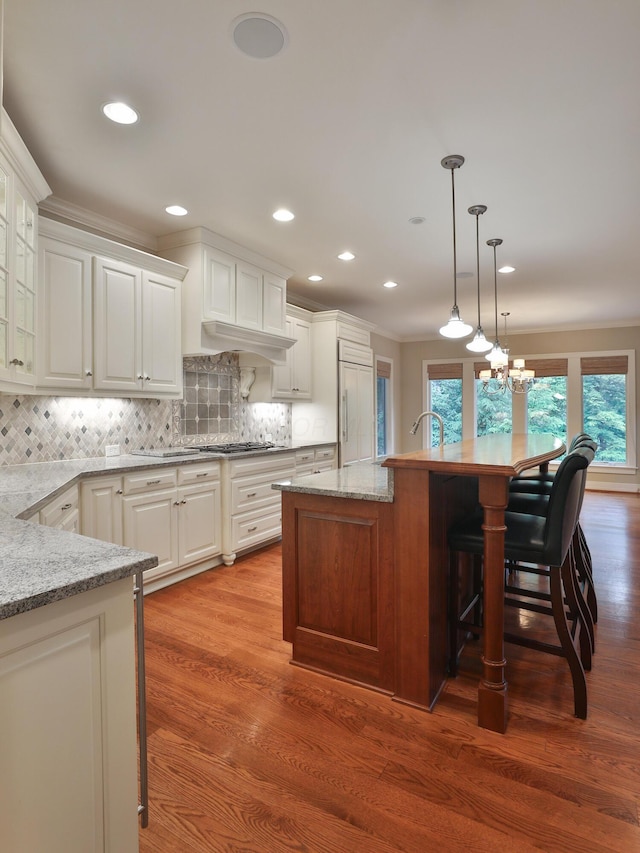 580 Keyes Ln, Worthington, OH 43085 - kitchen with paneled built in refrigerator, a kitchen bar, tasteful backsplash, light stone countertops, and white cabinetry