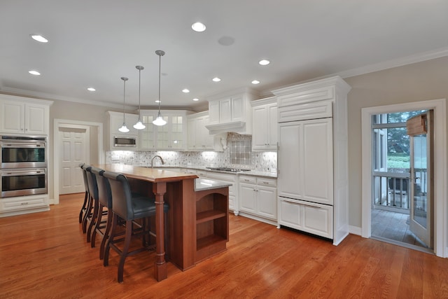 580 Keyes Ln, Worthington, OH 43085 - kitchen featuring built in appliances, ornamental molding, white cabinets, backsplash, and a kitchen bar