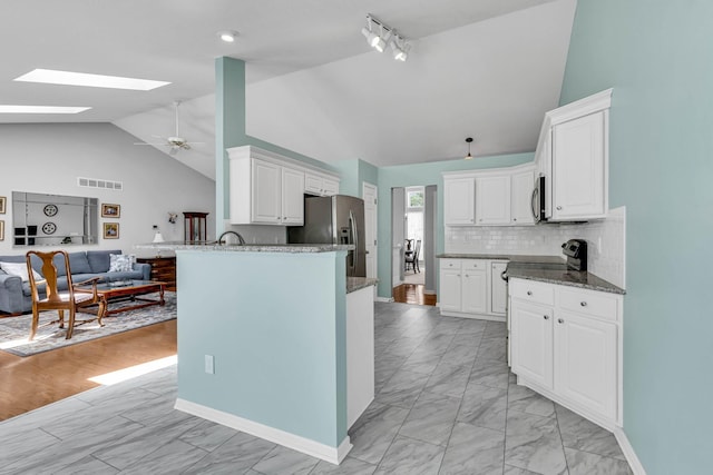 180 Locust Curve Dr, Delaware, OH 43015 - kitchen featuring stainless steel appliances, open floor plan, a skylight, light marble finish floors, and dark stone counters