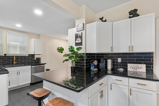 185 S Princeton Ave, Columbus, OH 43223 - kitchen with stainless steel dishwasher, tasteful backsplash, white cabinetry, a kitchen bar, and dark wood-style floors