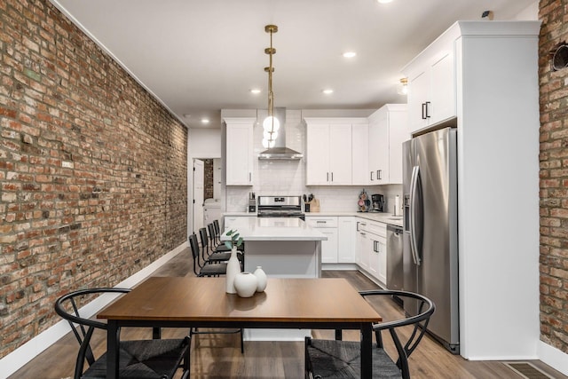 887-891 S 22nd St, Columbus, OH 43206 - kitchen featuring wall chimney exhaust hood, brick wall, appliances with stainless steel finishes, light countertops, and white cabinetry
