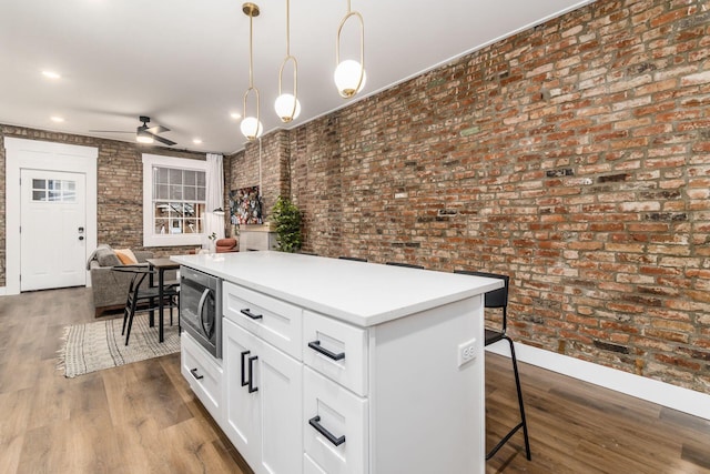 887-891 S 22nd St, Columbus, OH 43206 - kitchen with stainless steel microwave, a kitchen breakfast bar, decorative light fixtures, open floor plan, and ceiling fan