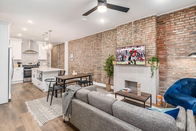 887-891 S 22nd St, Columbus, OH 43206 - living room featuring a ceiling fan, brick wall, light wood-style floors, recessed lighting, and a tile fireplace