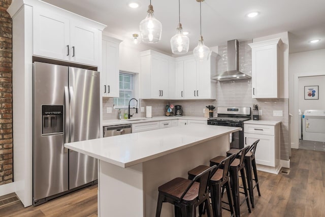 887-891 S 22nd St, Columbus, OH 43206 - kitchen featuring stainless steel appliances, wall chimney range hood, wood finished floors, washer / dryer, and recessed lighting