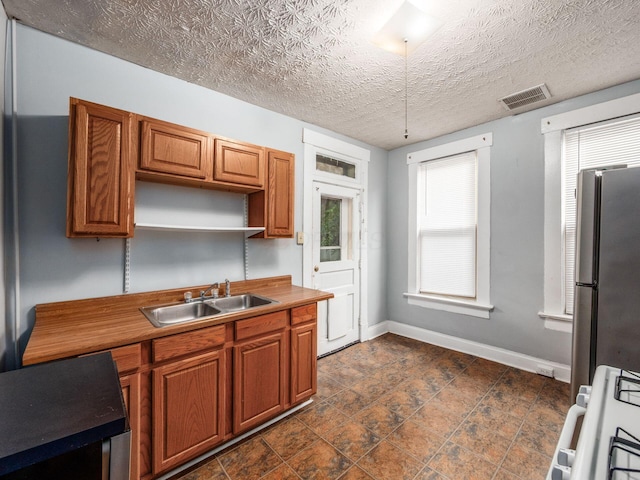 116-118 E Hudson St, Columbus, OH 43202 - kitchen with freestanding refrigerator, range, a textured ceiling, brown cabinetry, and open shelves