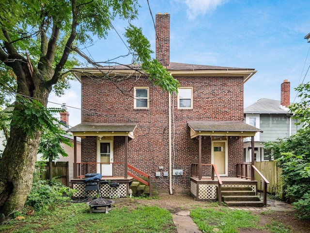 116-118 E Hudson St, Columbus, OH 43202 - rear view of house with an outdoor fire pit, a wooden deck, brick siding, and a chimney