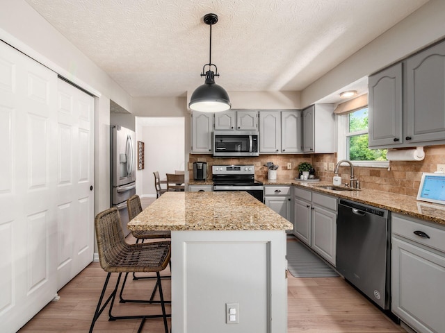 3552 Smiley Rd, Hilliard, OH 43026 - kitchen featuring appliances with stainless steel finishes, gray cabinets, tasteful backsplash, a kitchen island, and a kitchen breakfast bar