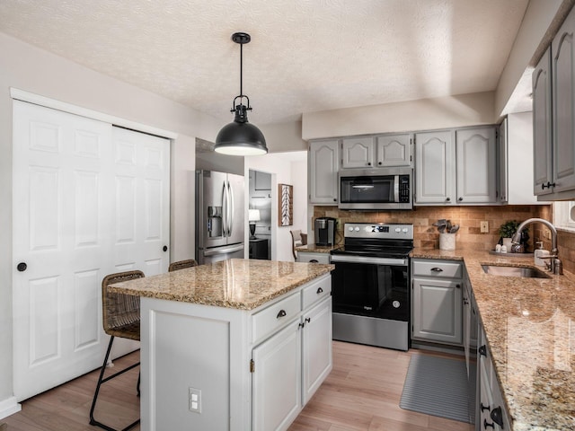 3552 Smiley Rd, Hilliard, OH 43026 - kitchen with appliances with stainless steel finishes, gray cabinetry, tasteful backsplash, light wood-type flooring, and a kitchen island