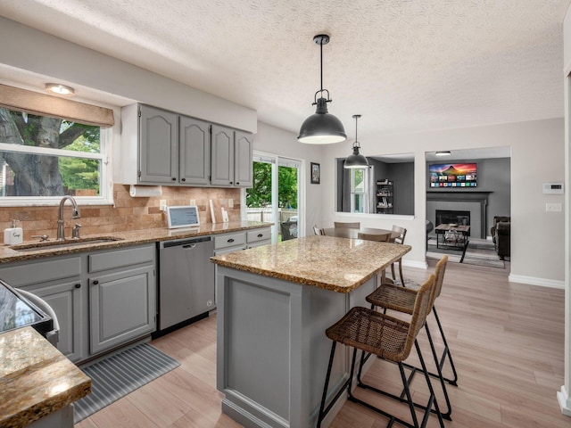 3552 Smiley Rd, Hilliard, OH 43026 - kitchen featuring stainless steel dishwasher, gray cabinetry, a center island, decorative backsplash, and light wood-style flooring