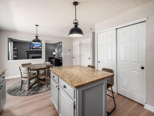 3552 Smiley Rd, Hilliard, OH 43026 - kitchen with light wood-style floors, a center island, a kitchen breakfast bar, pendant lighting, and a textured ceiling