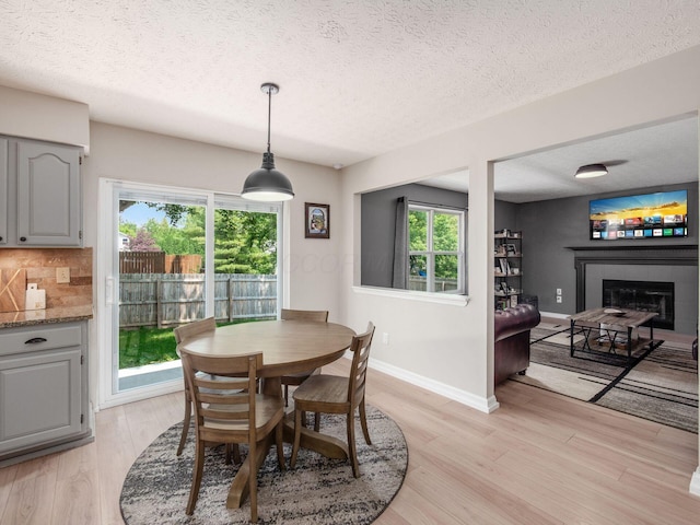 3552 Smiley Rd, Hilliard, OH 43026 - dining space featuring a glass covered fireplace, a textured ceiling, and light wood-style flooring