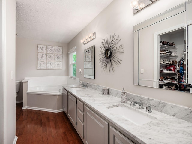 3552 Smiley Rd, Hilliard, OH 43026 - bathroom with wood finished floors, a bath, double vanity, and a textured ceiling
