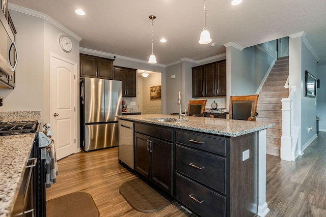 123 Schellinger St, Delaware, OH 43015 - kitchen featuring appliances with stainless steel finishes, wood finished floors, ornamental molding, an island with sink, and dark brown cabinetry