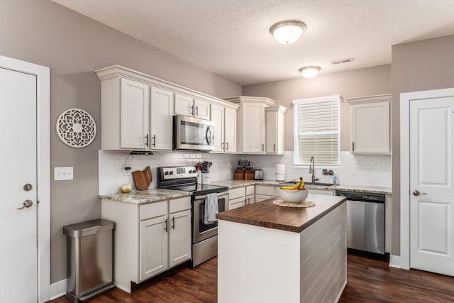 2020 Edison St, Newark, OH 43055 - kitchen with appliances with stainless steel finishes, backsplash, dark wood-style floors, a center island, and a textured ceiling