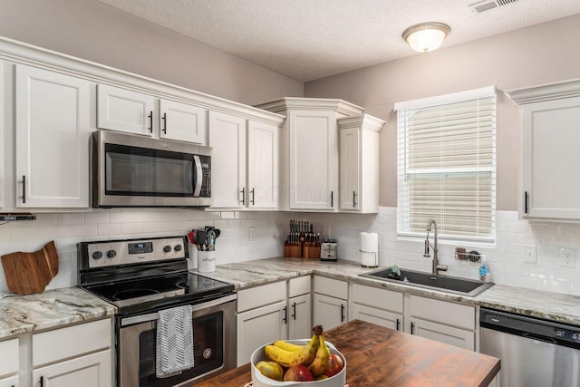 2020 Edison St, Newark, OH 43055 - kitchen with appliances with stainless steel finishes, backsplash, a textured ceiling, and white cabinets