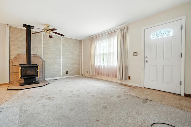 814 Gilmore Dr, Reynoldsburg, OH 43068 - unfurnished living room featuring plenty of natural light, a ceiling fan, brick wall, a wood stove, and carpet floors