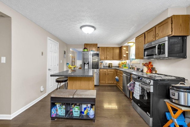 8711 Blessing Dr, Powell, OH 43065 - kitchen featuring stainless steel appliances, dark wood-type flooring, a center island, dark countertops, and a textured ceiling