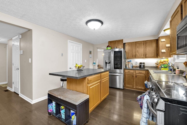 8711 Blessing Dr, Powell, OH 43065 - kitchen with stainless steel appliances, dark wood-style flooring, a kitchen island, brown cabinets, and dark countertops