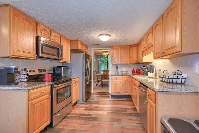 4883 Powderhorn Ln Unit 3, Westerville, OH 43081 - kitchen featuring appliances with stainless steel finishes, wood finished floors, light stone counters, and backsplash