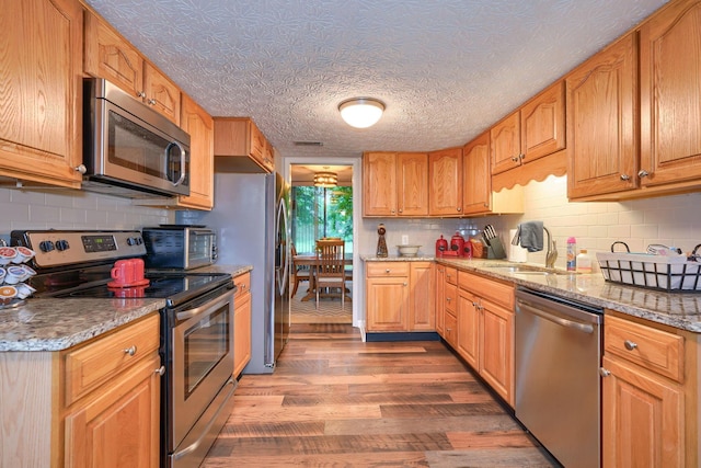 4883 Powderhorn Ln Unit 3, Westerville, OH 43081 - kitchen featuring stainless steel appliances, wood finished floors, decorative backsplash, and light stone countertops