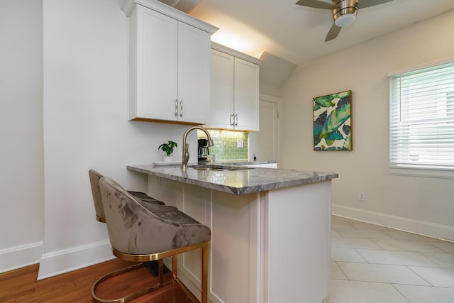 338 Sheldon Ave, Columbus, OH 43207 - kitchen featuring a peninsula, ceiling fan, stone counters, white cabinets, and a breakfast bar area